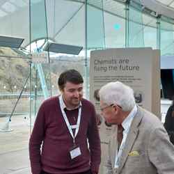 A member of our team speaks with one of the delegates at the Science and the Parliament event in front of a banner that reads "Chemists are fixing the future"