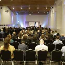 Scores of delegates sit in Our Dynamic Earth and watch one of the discussions